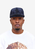 Model wearing the Imaan Vouge 5-Panel Noble Hat in black velvet with beaded trim